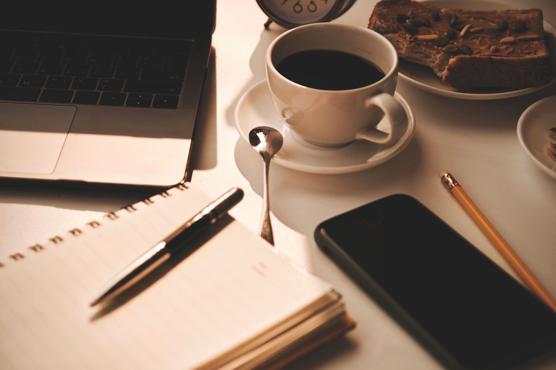 Espacio de trabajo acogedor con café, cuaderno y aperitivos, ideal para ser productivo.