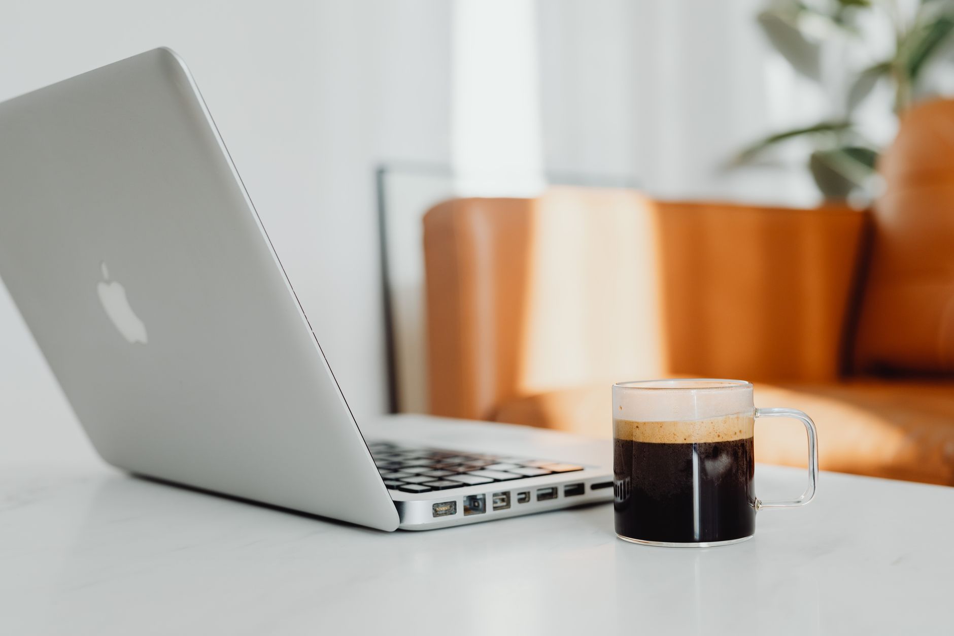 Salón acogedor con un portátil y una taza de café sobre el escritorio.
